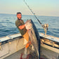 Angler holding a bluefin tuna, Giant Bluefin Series rod in the holder