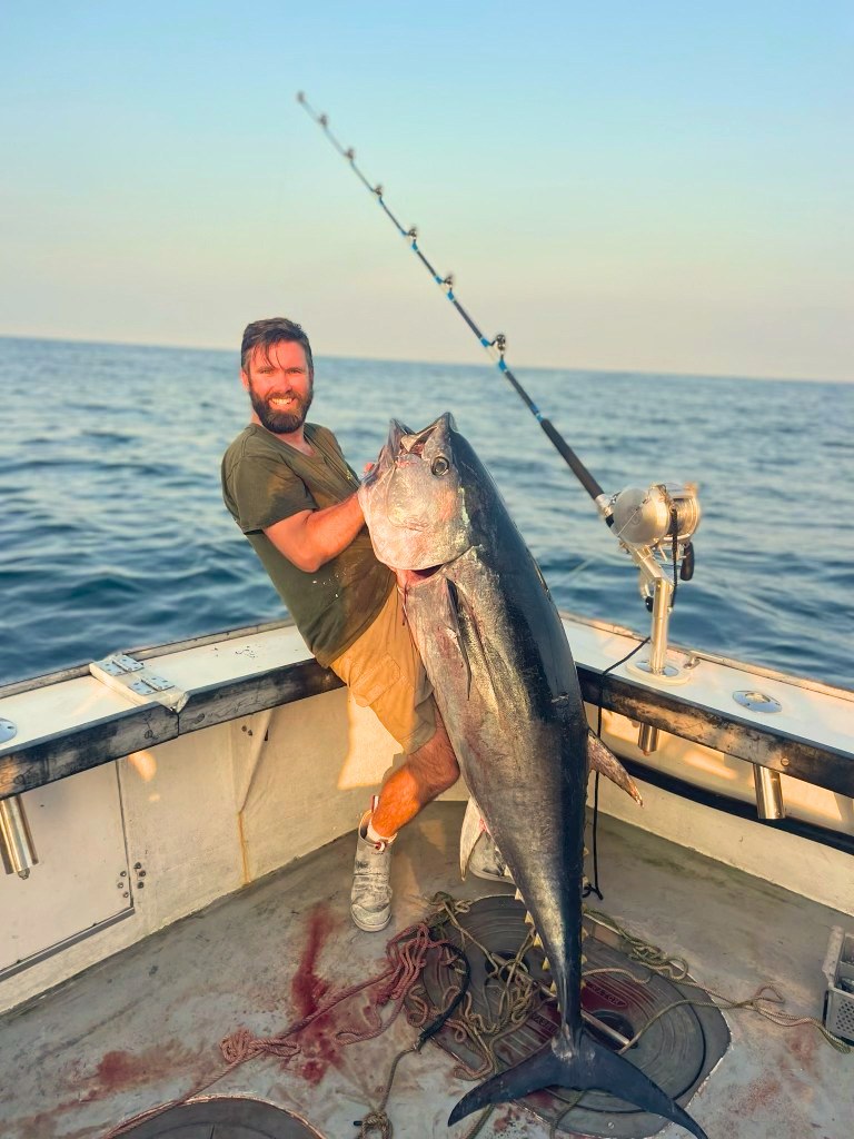 Angler holding a bluefin tuna, Giant Bluefin Series rod in the holder