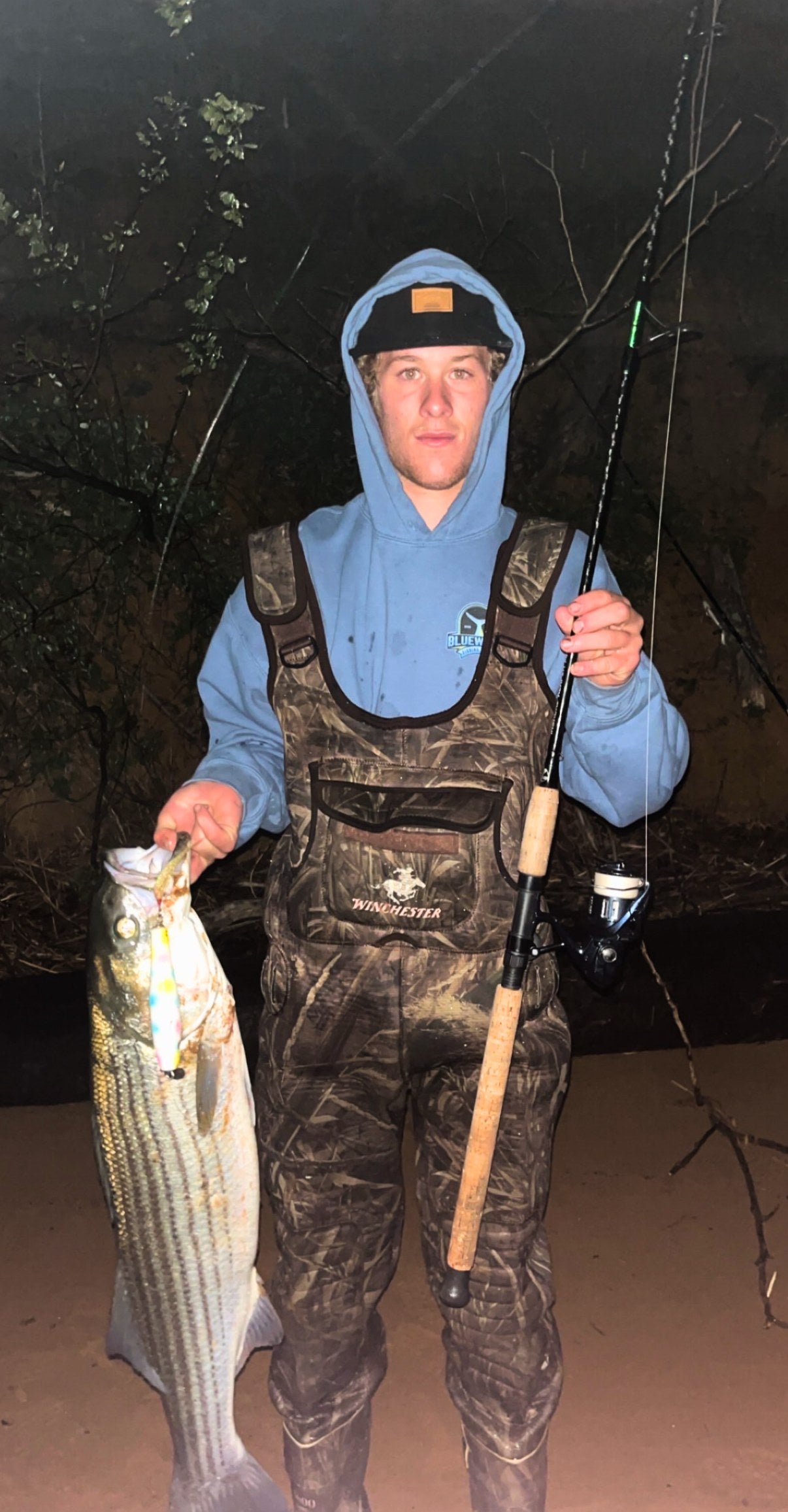 Angler with a striped bass and Inshore Reaper rod at night