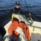 Angler with a striped bass on an Inshore Reaper rod, bay behind