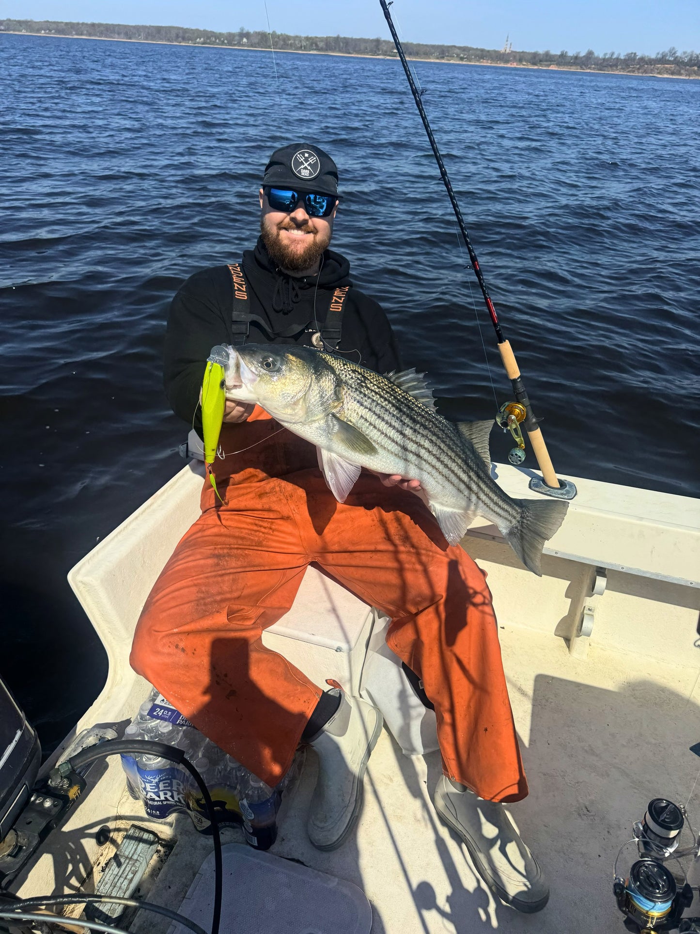 Angler with a striped bass on an Inshore Reaper rod, bay behind