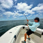 Pelagic Sniper rod bent deep from the bow under a cloudy sky