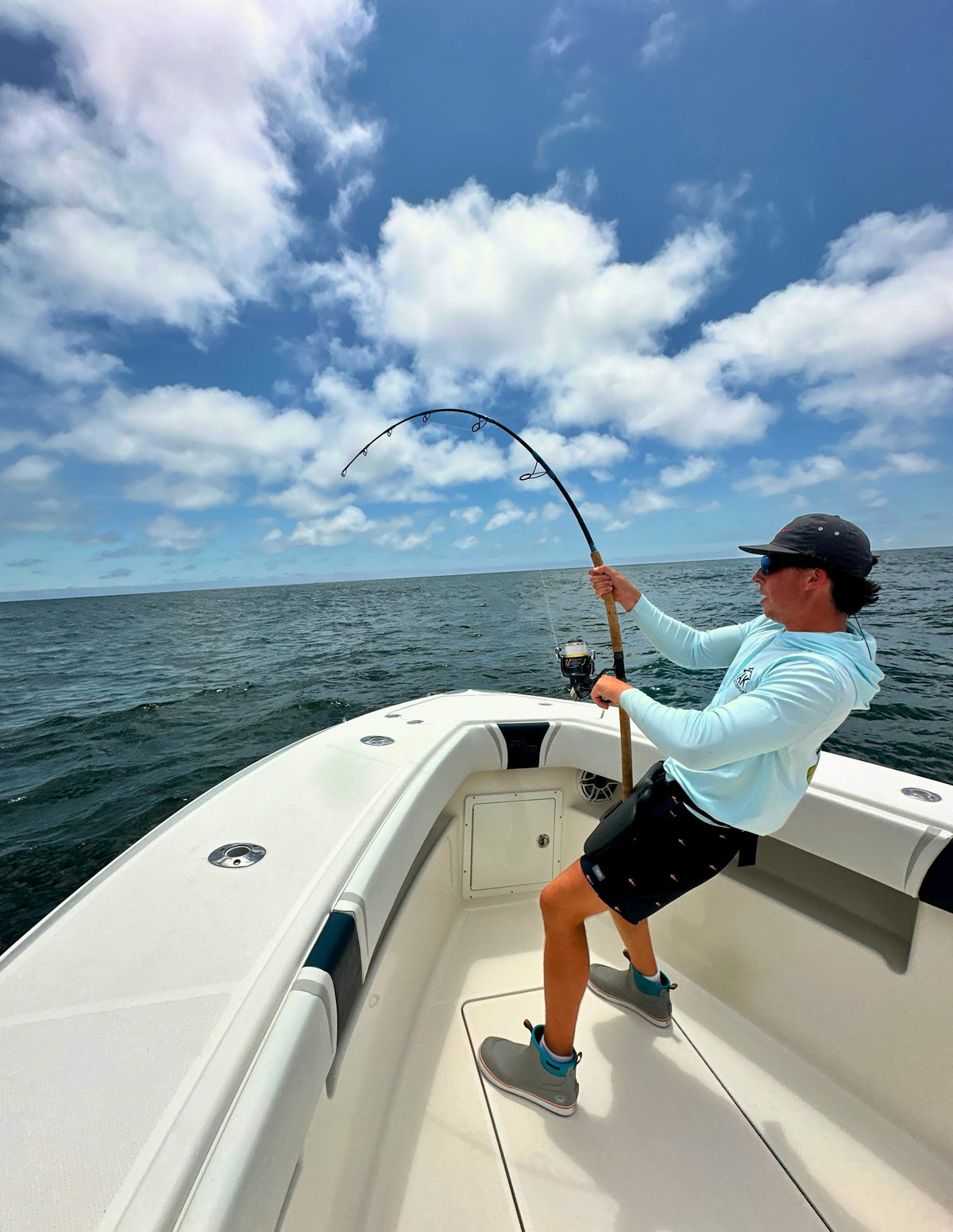 Pelagic Sniper rod bent deep from the bow under a cloudy sky