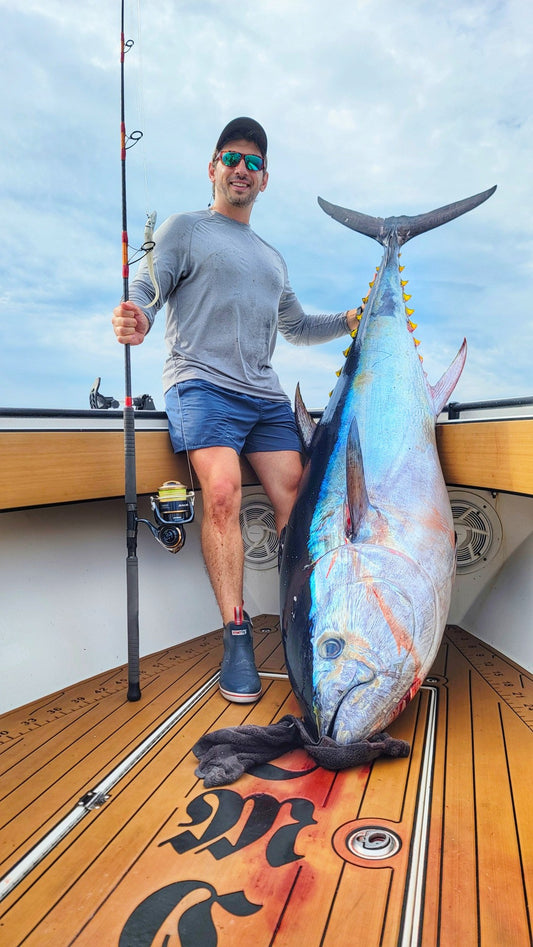 Angler on deck with a yellowfin tuna and Pelagic Sniper rod