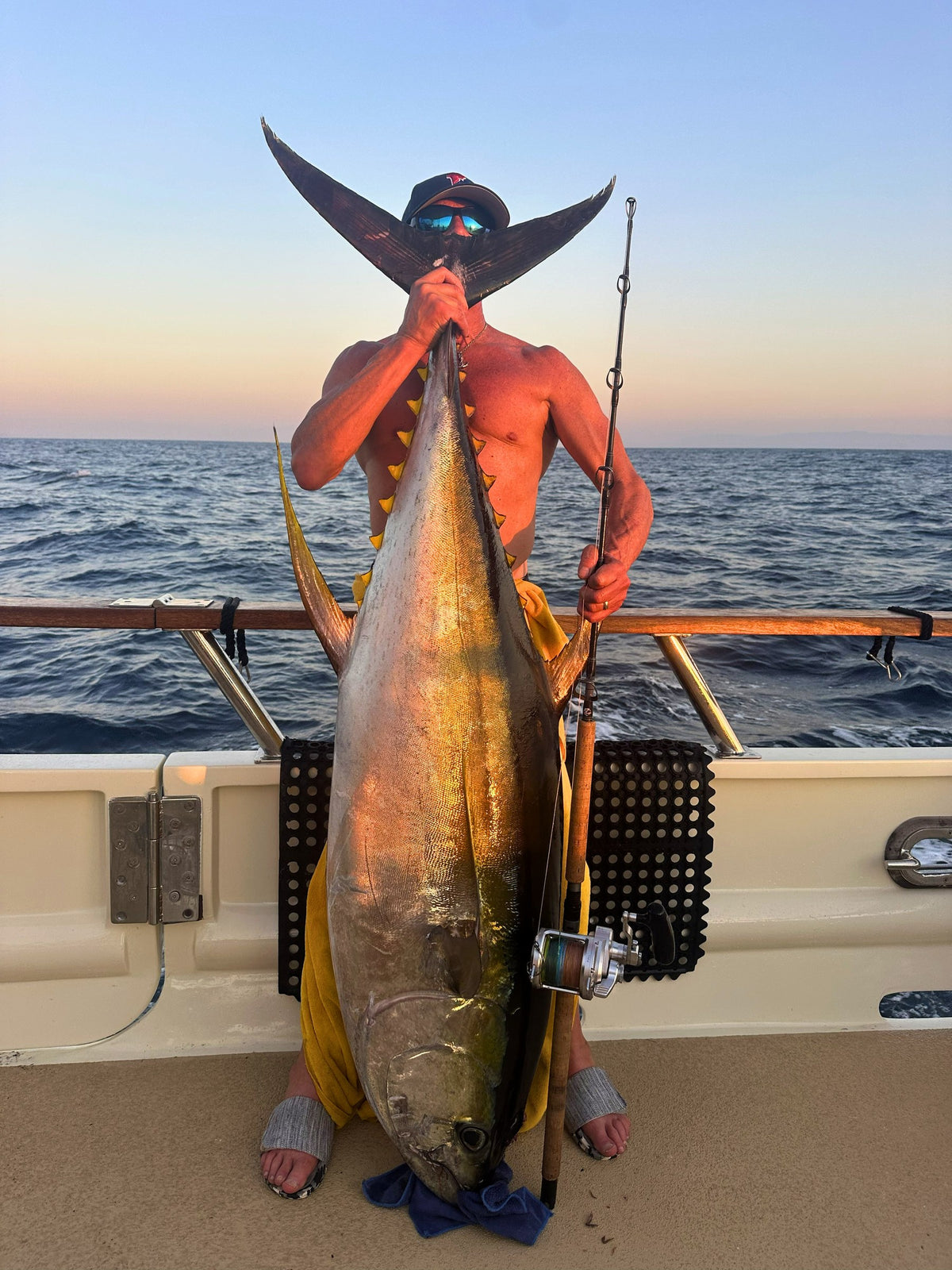 Angler with a yellowfin tuna and Phantom Jigger rod at sunset