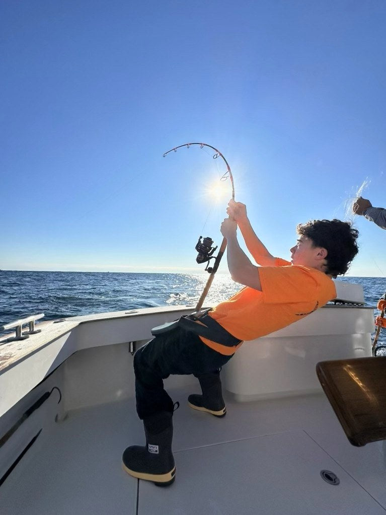 Angler leaning back into a Phantom Jigger rod, sun behind