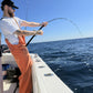 Angler in orange bibs with a Phantom Jigger rod bent over the gunwale