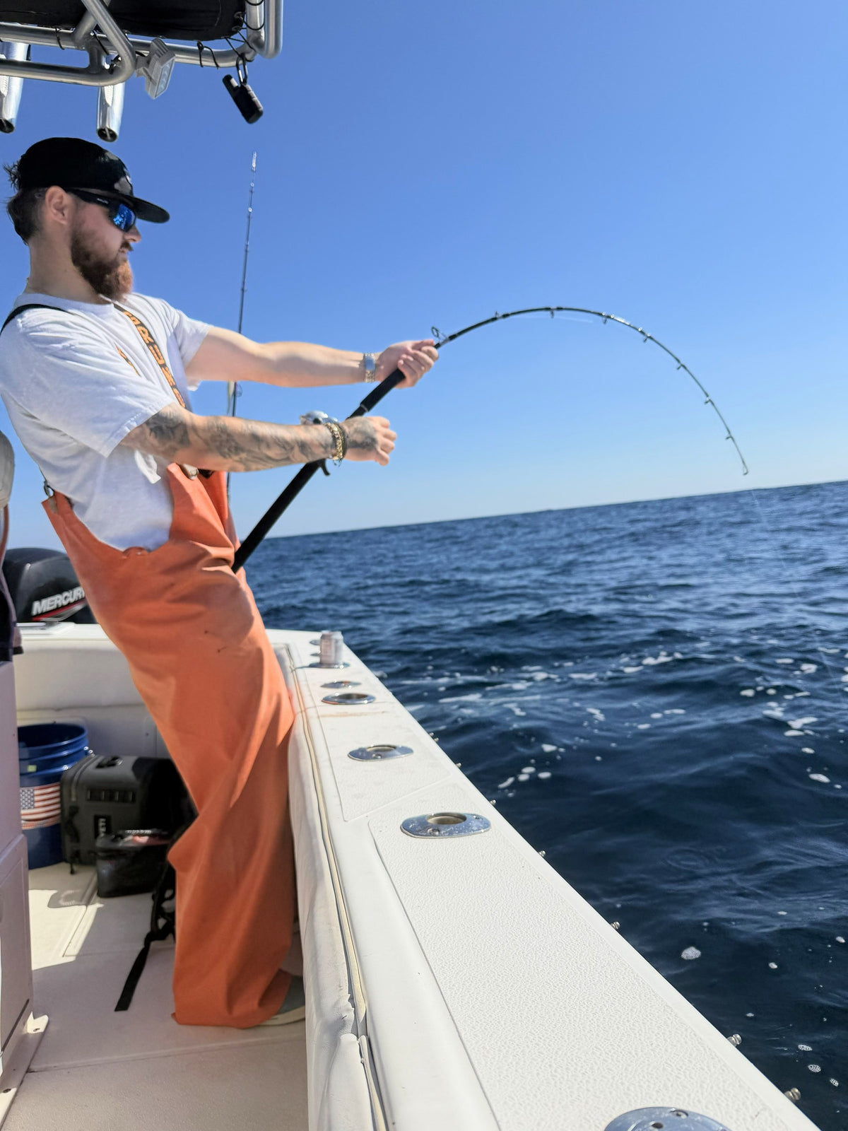 Angler in orange bibs with a Phantom Jigger rod bent over the gunwale