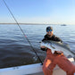 Angler in orange bibs with a striped bass caught on a Tiderunner rod
