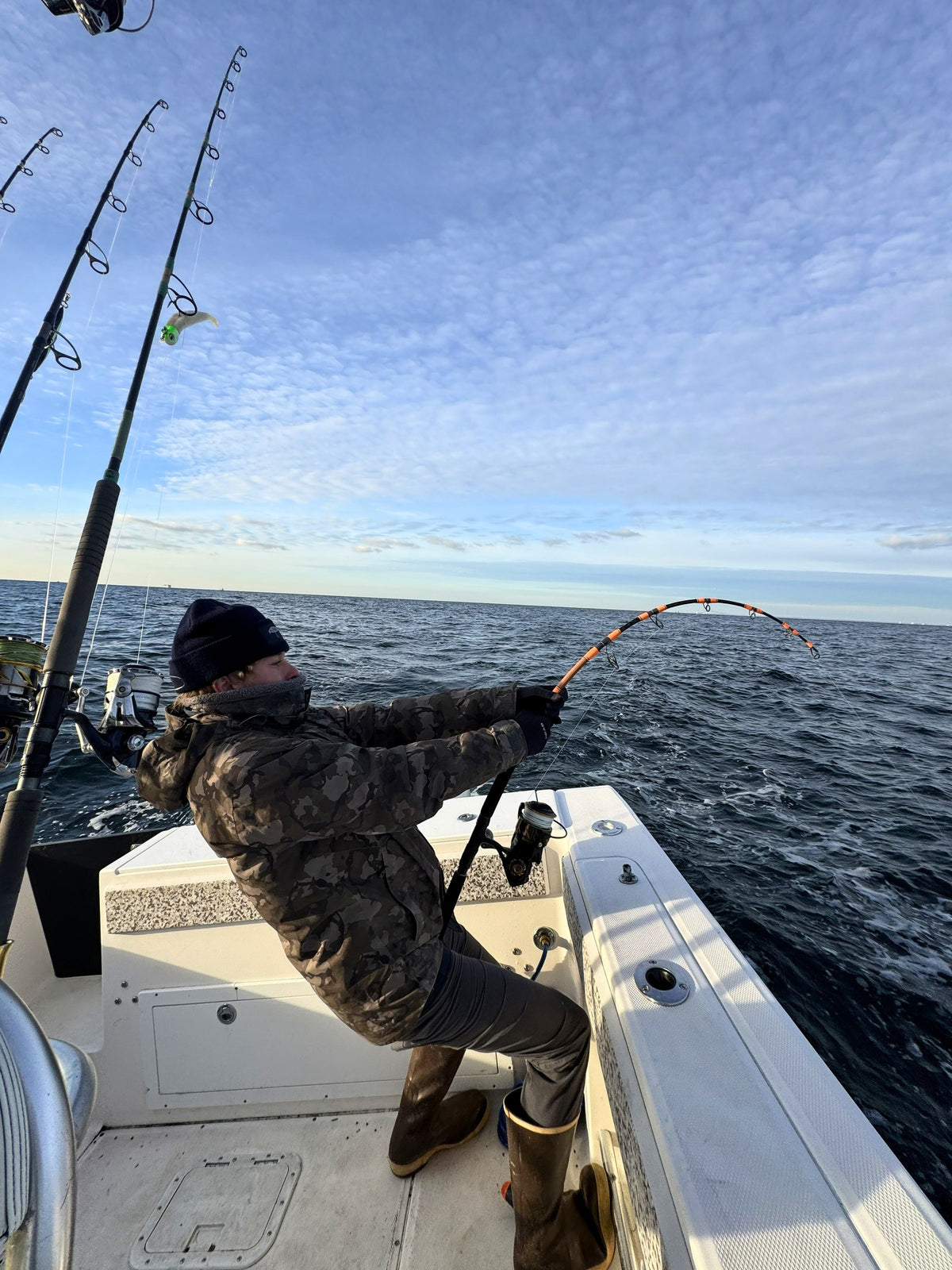 Angler in camo fighting a fish on a Vert Giant jigging rod
