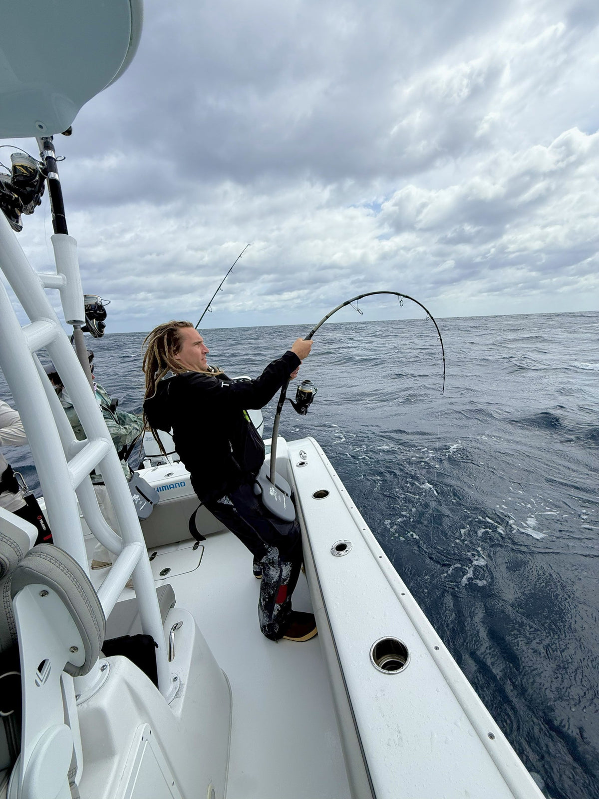 Vert Giant topwater rod bent on a fish, overcast sky