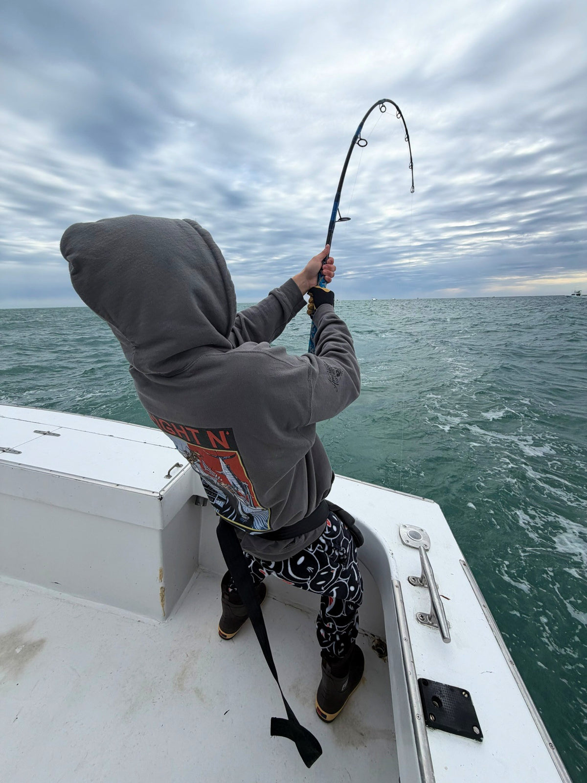 Angler in a hoodie leaning into a Vert Giant topwater rod